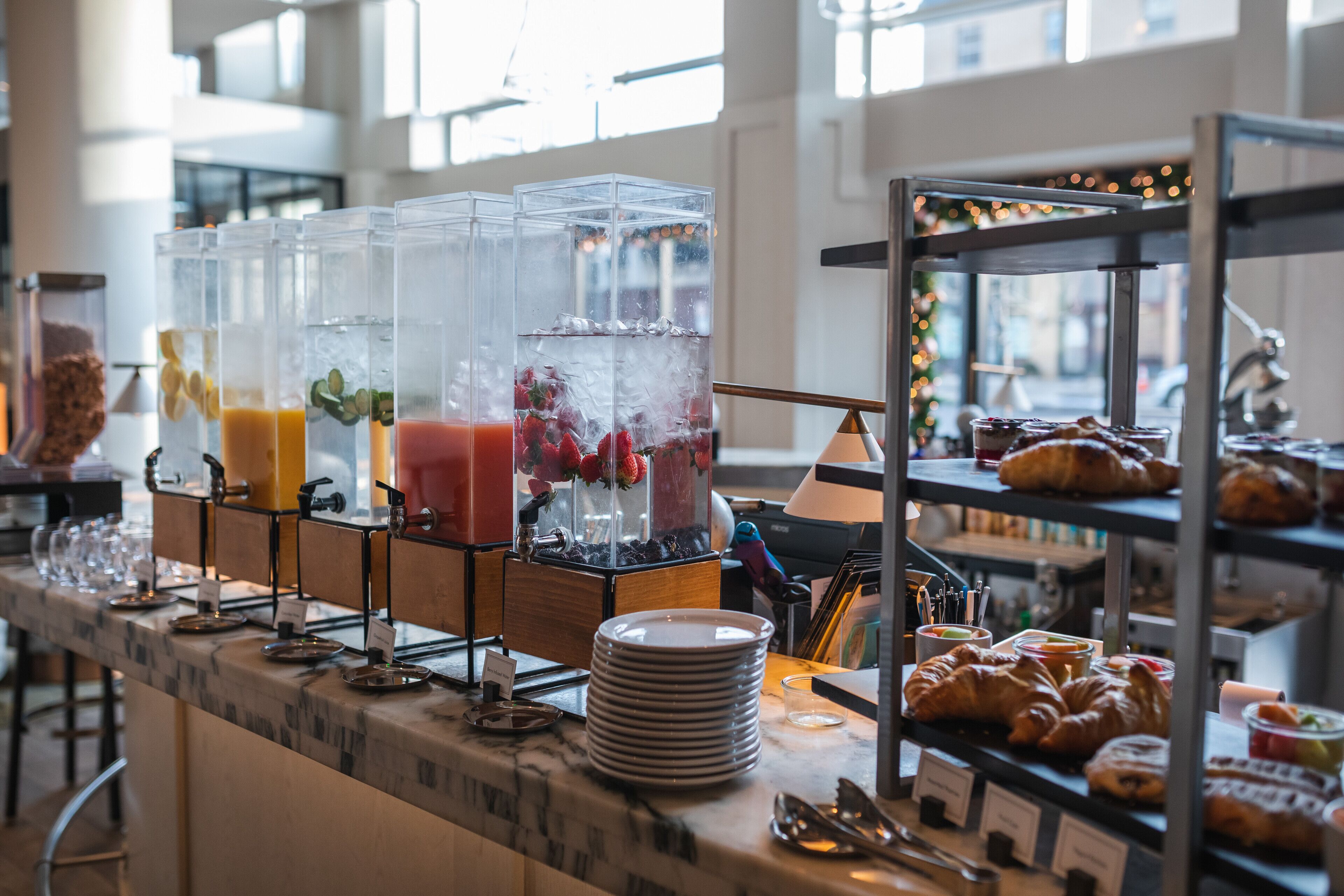 Una barra de desayuno con diversas bebidas, platos y pasteles.