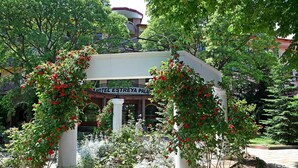 Un jardín con un pabellón y un cartel que indica Hotel Estreya Palace.