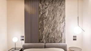 A modern bedroom with a bed, a nightstand, a wall-mounted light, and a small table. - Resort Miramonti (Forte dei Marmi)