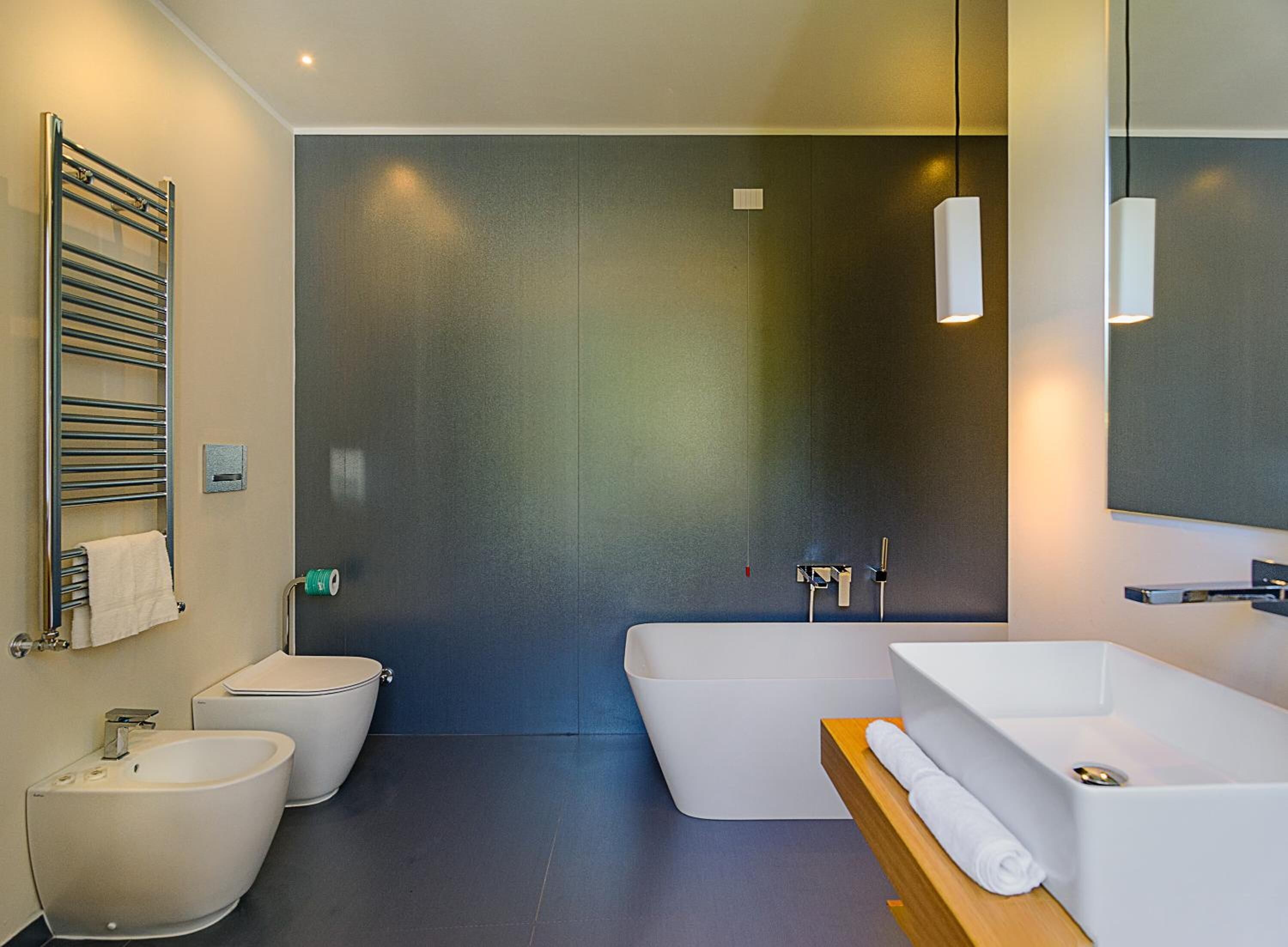A modern bathroom with a bathtub, a toilet, and a bidet.