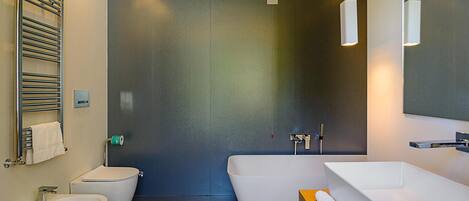 A modern bathroom with a bathtub, a toilet, and a bidet.