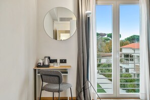 Una habitación con escritorio, silla, cafetera y vistas por la ventana.