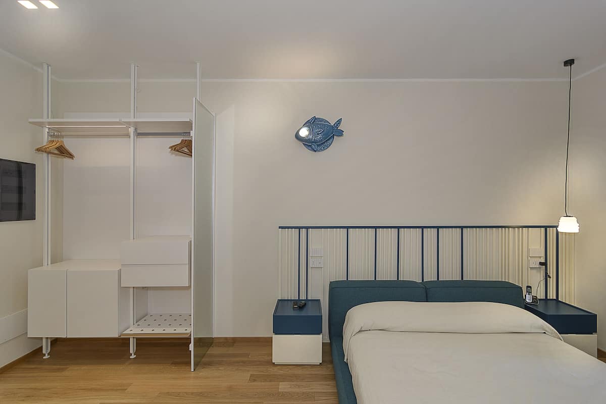 A bedroom with a bed, bedside tables, a wardrobe, and a wall-mounted light fixture.