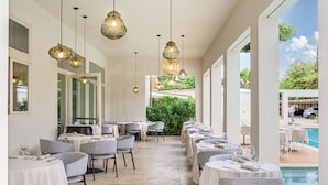 A restaurant with round tables, chairs, and hanging pendant lights. - Resort Miramonti (Forte dei Marmi)