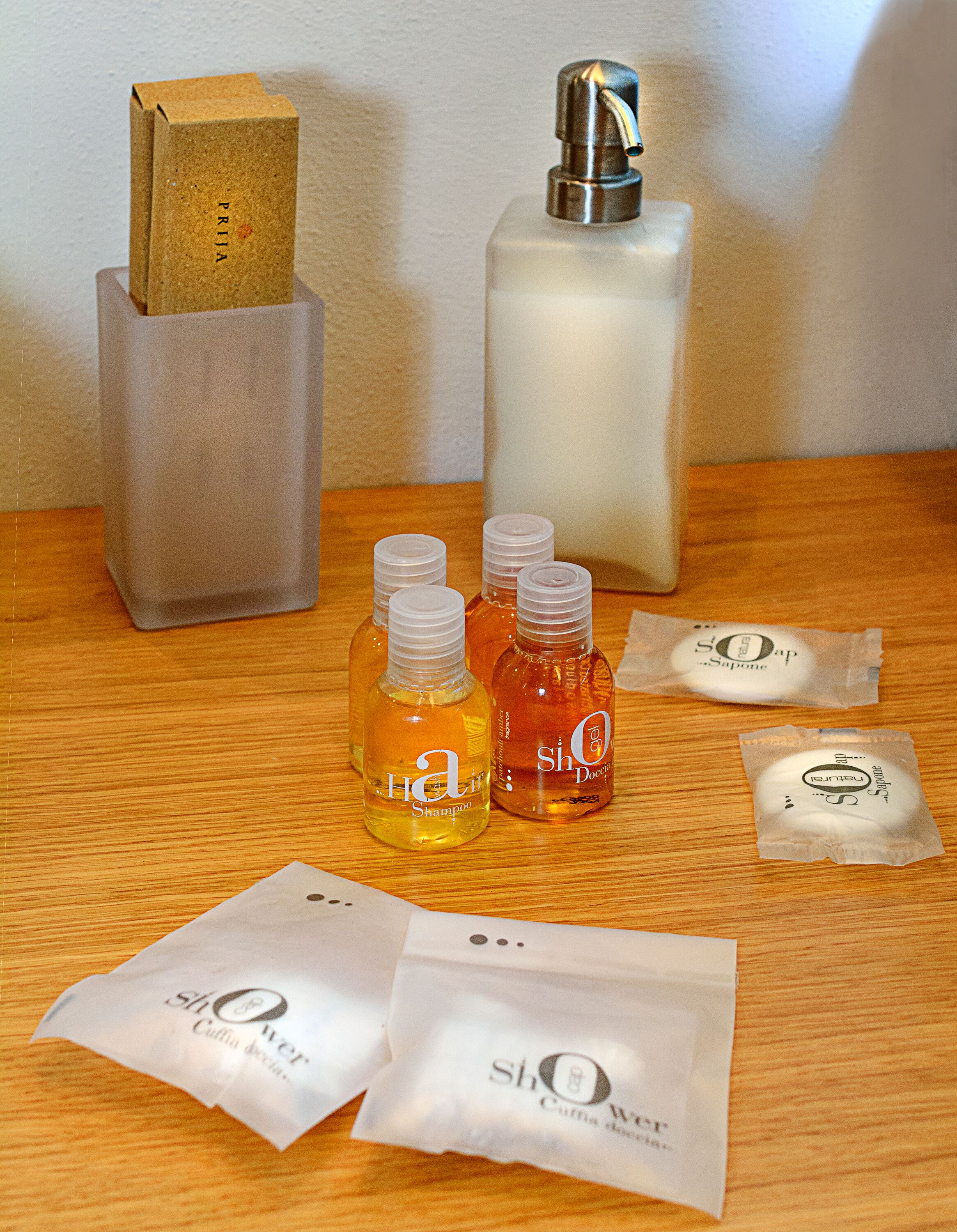 Una mesa de madera con diversos artículos de aseo, incluyendo botellas de champú, jabón y un frasco de perfume.