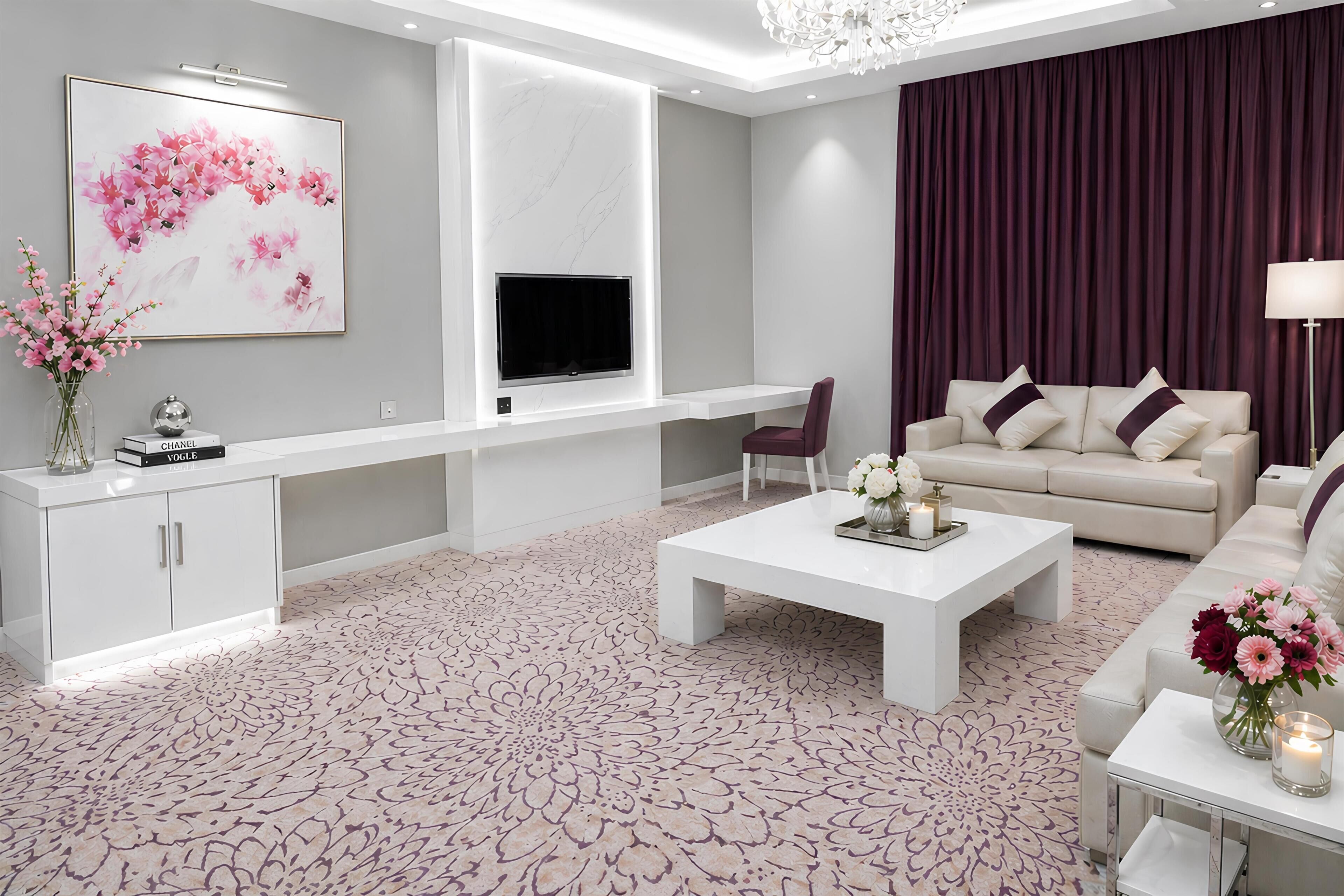 A modern living room with a flat-screen TV, a sofa, a coffee table, and decorative flowers.