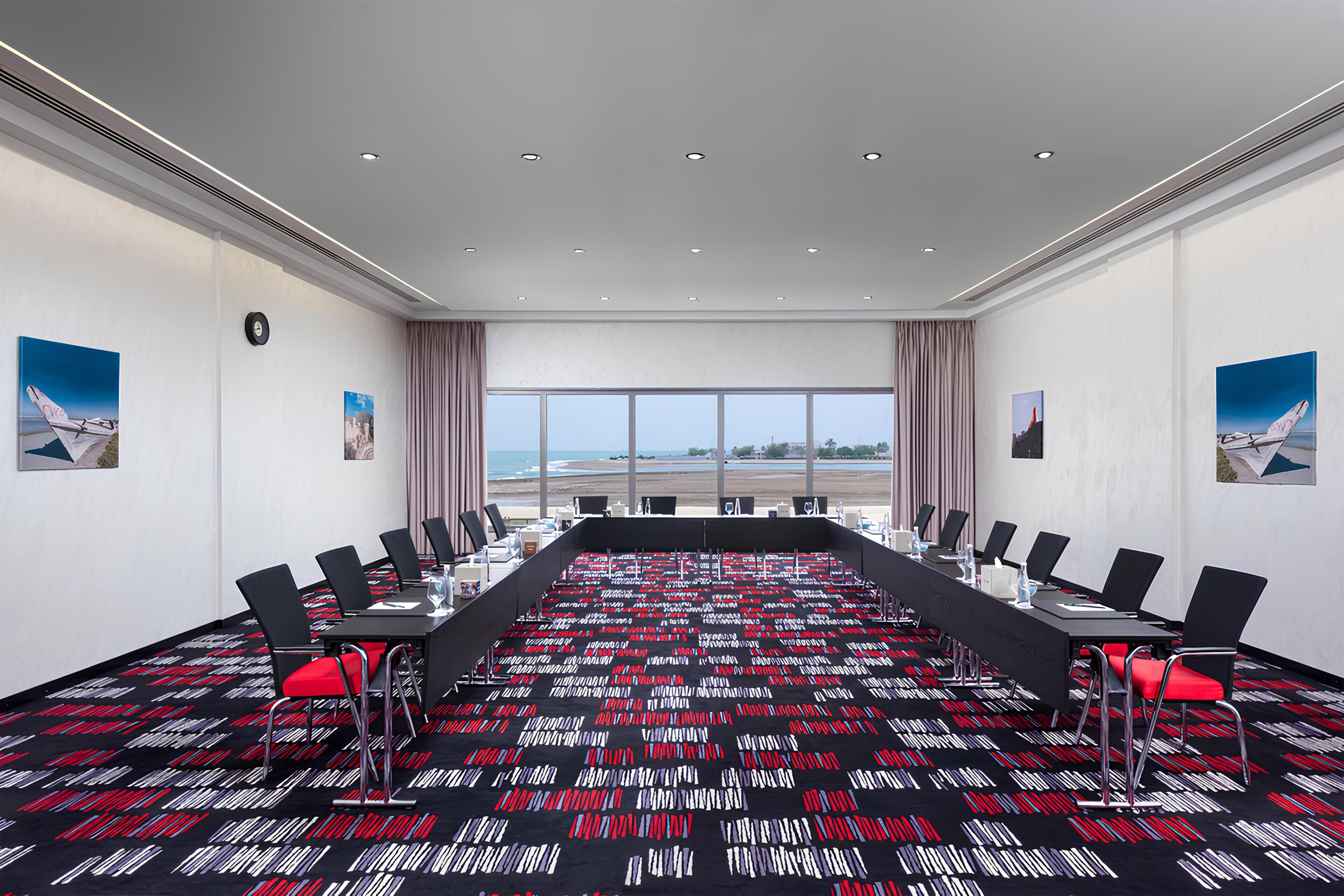 A conference room with a long table, chairs, and a view of the airport.