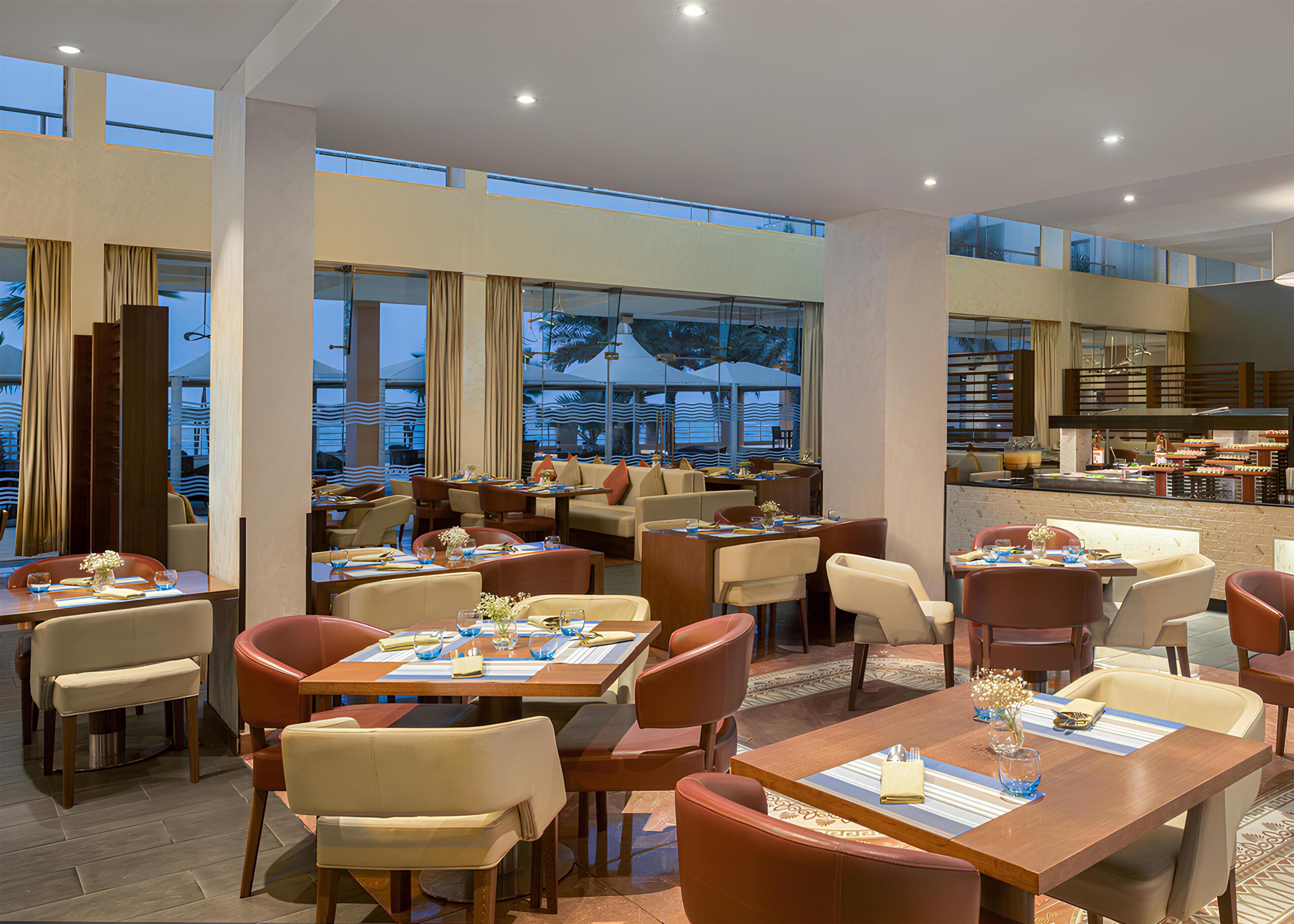 Ein geräumiges Restaurant mit mehreren Essbereichen, großen Fenstern und Blick ins Freie.