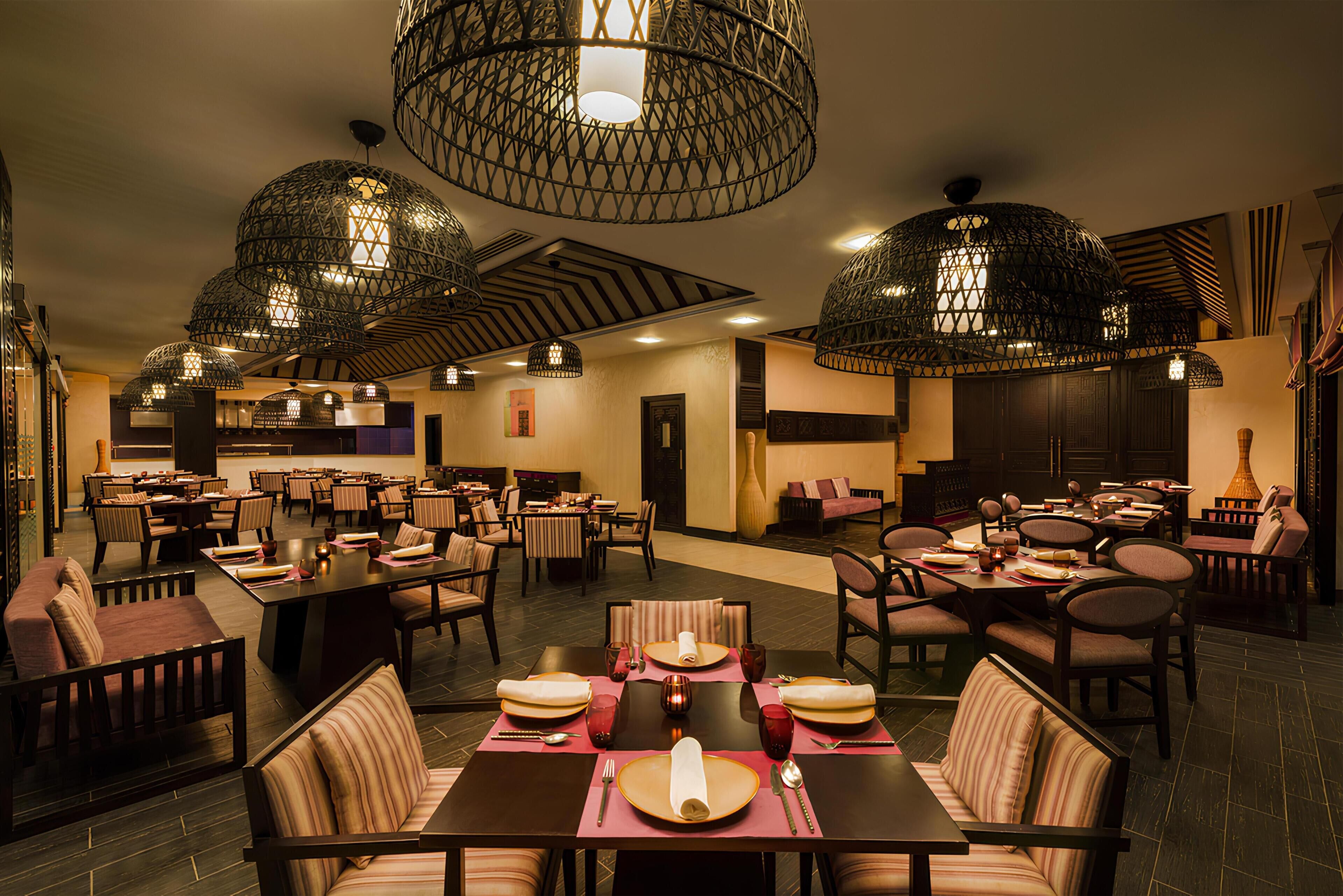 A restaurant with multiple dining tables, chairs, and hanging light fixtures.
