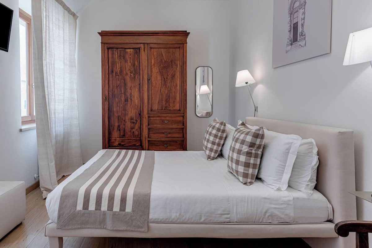 Een slaapkamer met een bed, een kledingkast, een spiegel en een lamp.