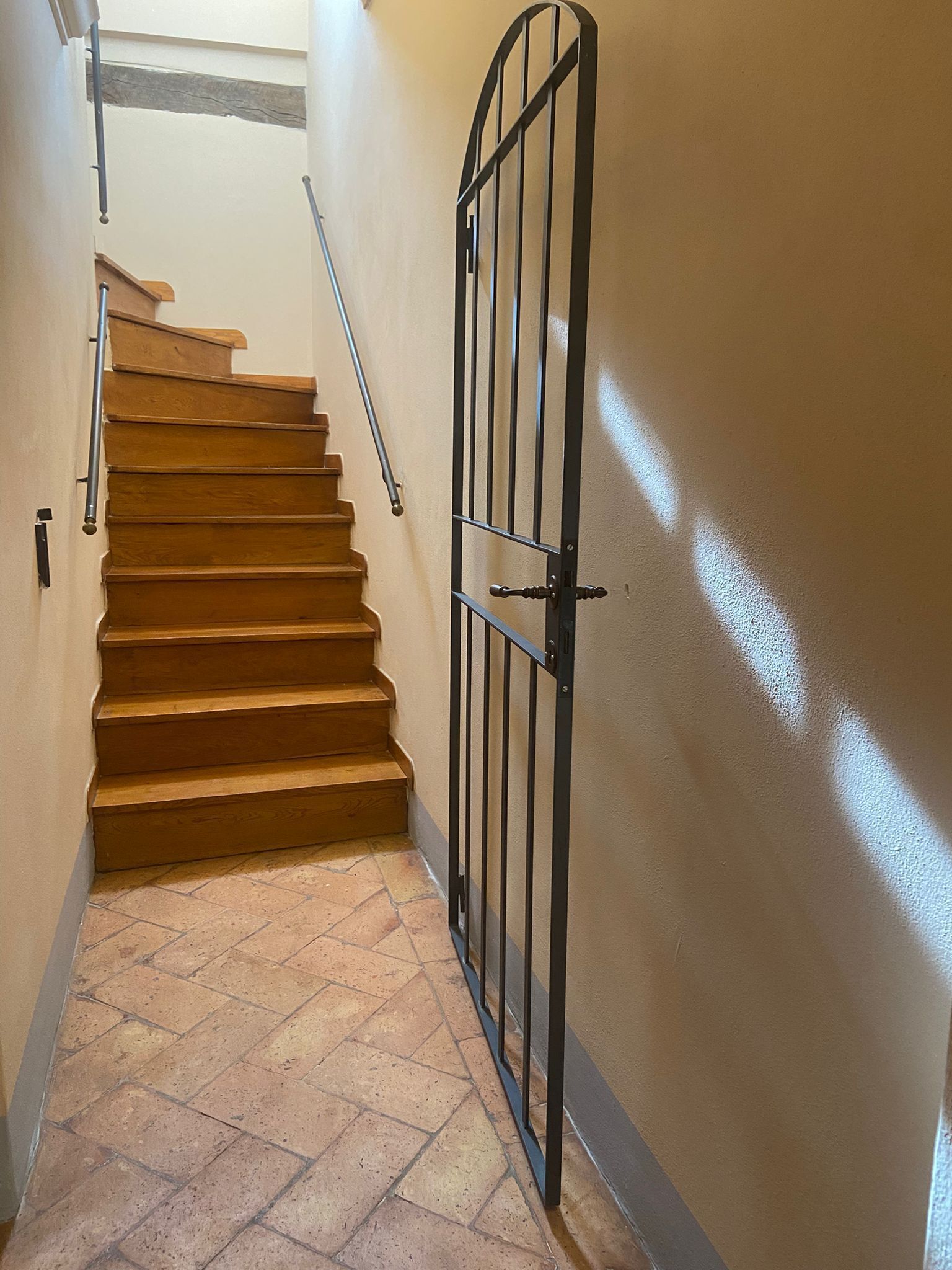 Una escalera de madera con peldaños y una reja metálica en la parte superior.