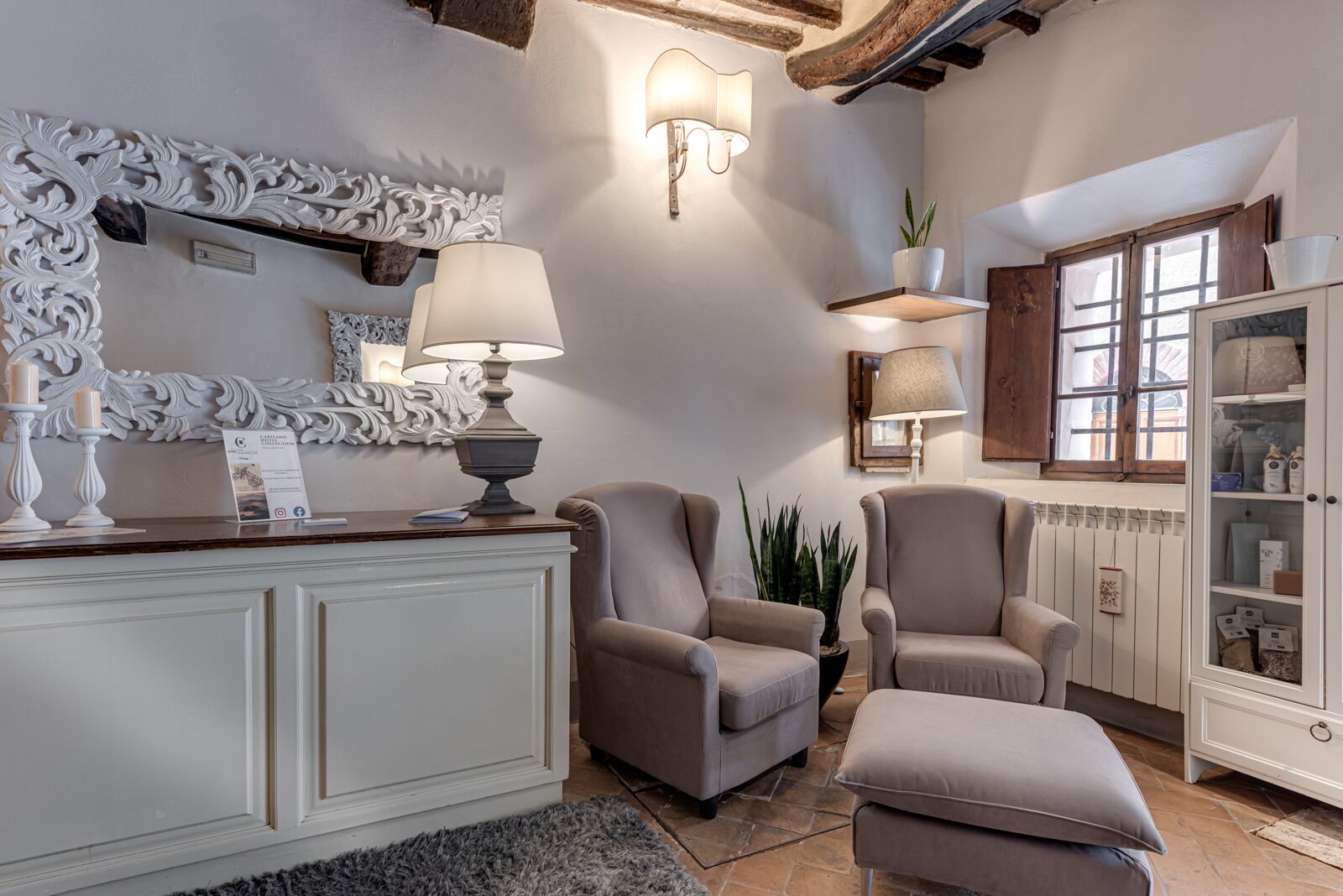 A cozy living room with a white fireplace, two armchairs, a coffee table, and a cabinet with storage.