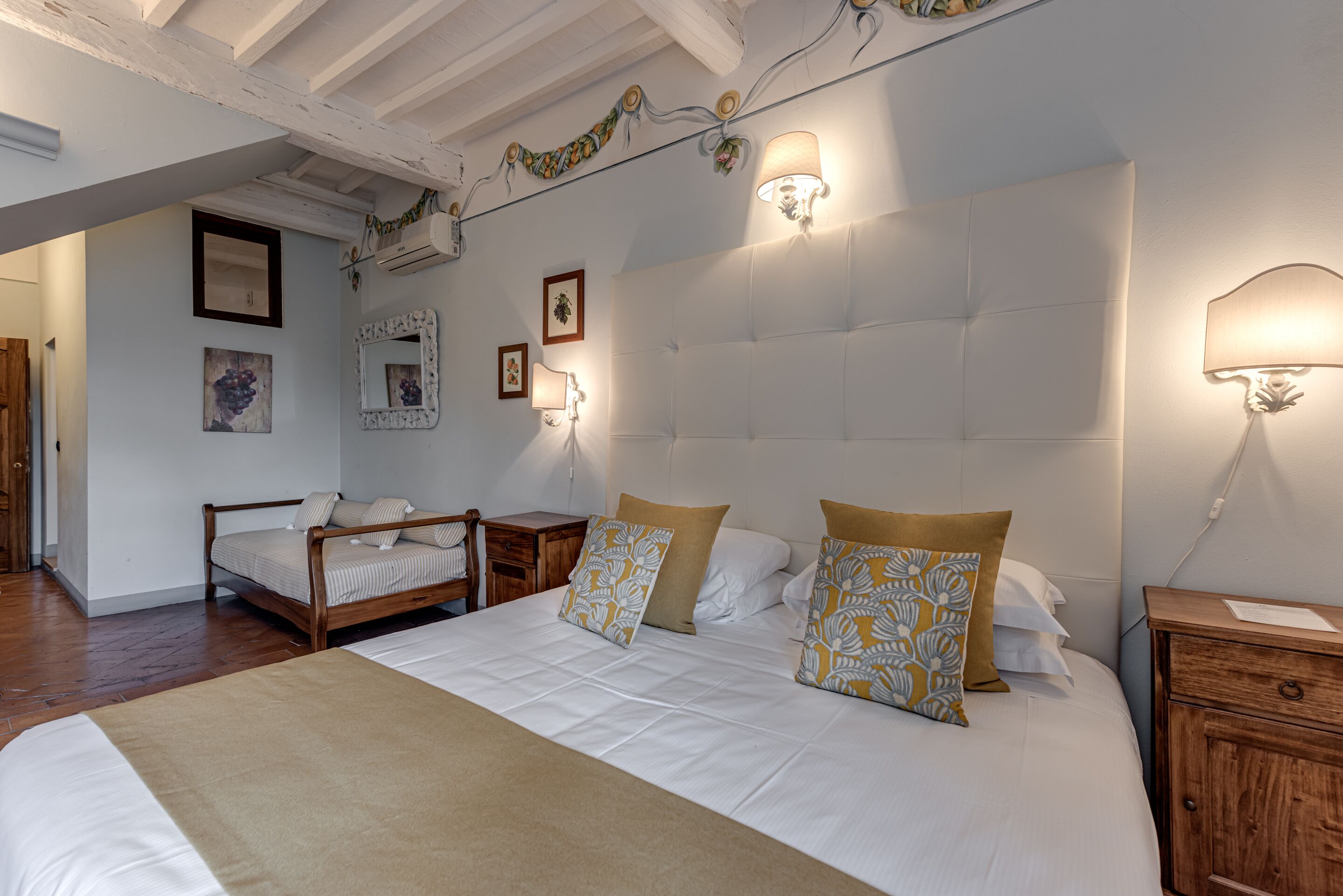 Un dormitorio con una cama grande, dos mesitas de noche, una mesita auxiliar de madera y una lámpara de pared.