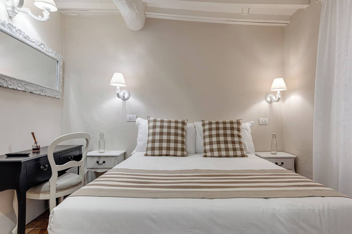 Een hotelkamer met een groot bed, twee bedlampen, een bureau met stoel en een spiegel aan de muur.