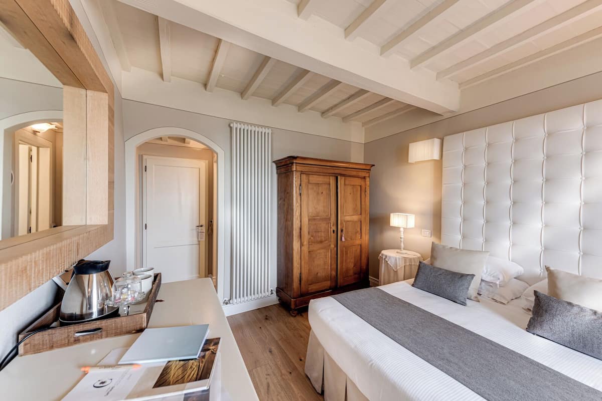 Een slaapkamer met een bed, nachtkastje, lamp, kledingkast en een spiegel.
