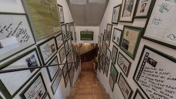 A staircase with framed photos and messages on the walls, leading to a pizzeria.