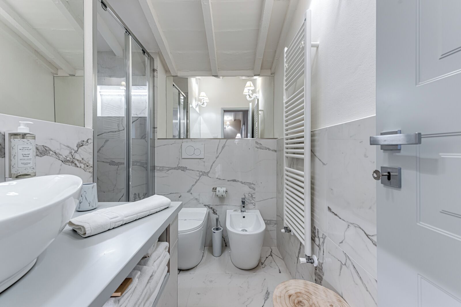 Een moderne badkamer met een marmeren wastafel, een hygiëneschuimer en een toilet.