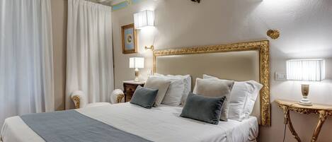 A hotel room with a large bed, a bedside table, a lamp, and a mirror.