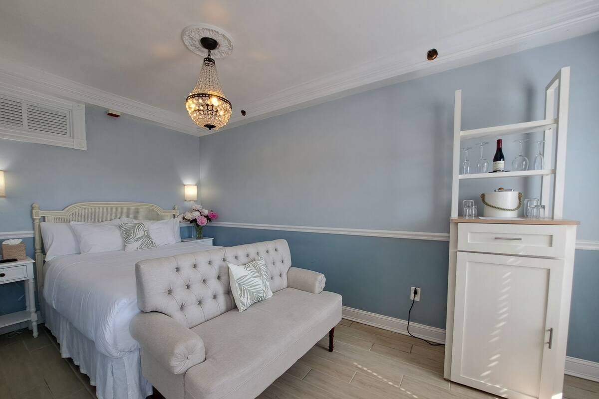 Quarto com cama, sofá, mesa de cabeceira, abajur, lustre e armário.