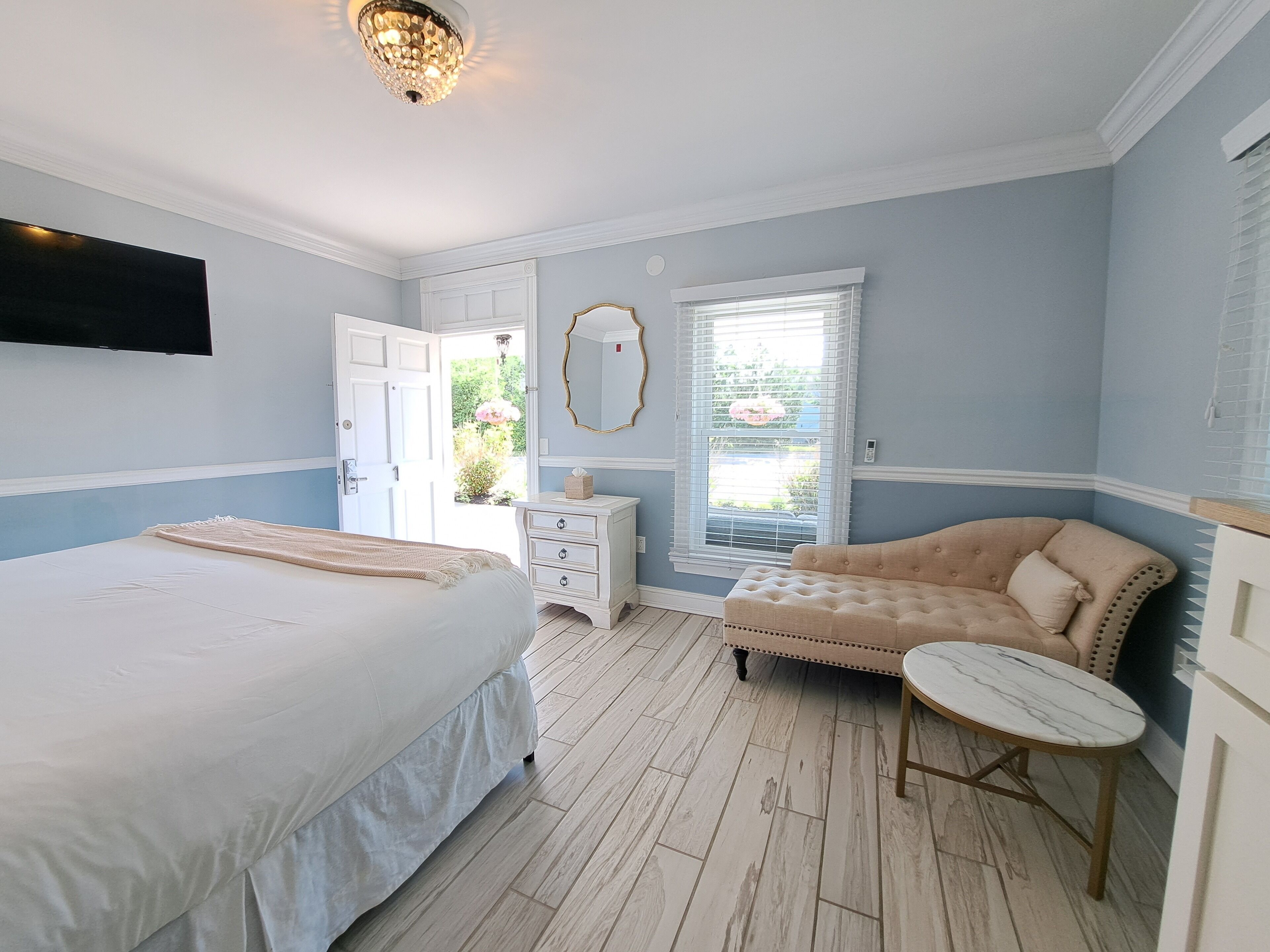 Un dormitorio con cama, cómoda, silla y una mesita.