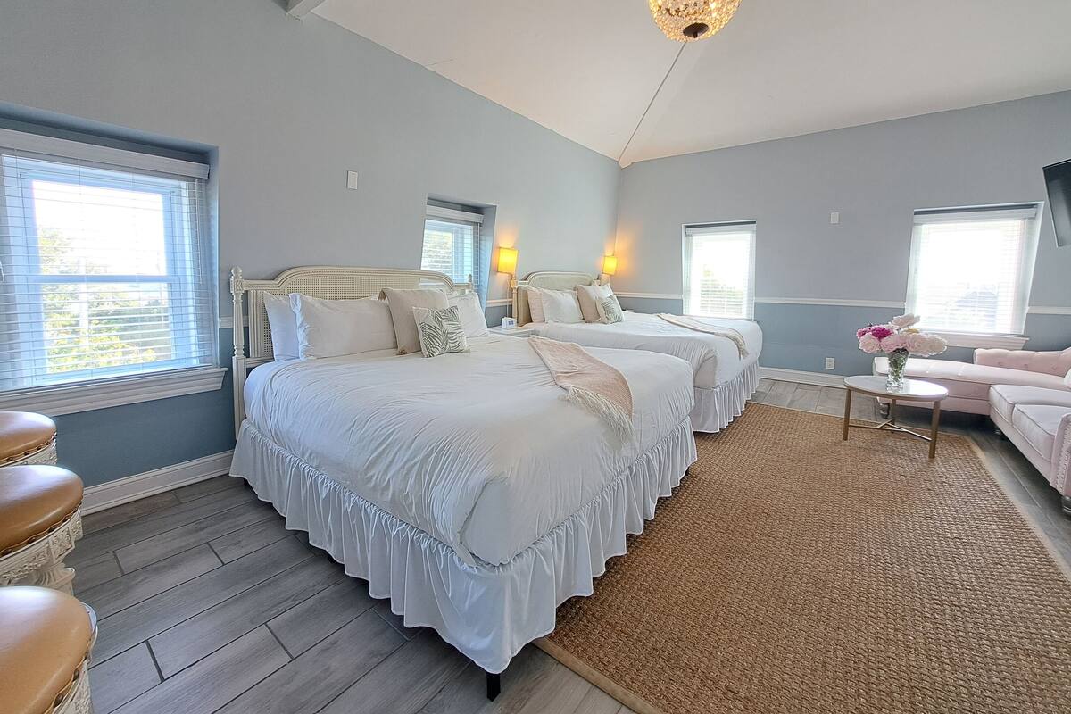 Quarto com duas camas, um candelabro e um sofá rosa.