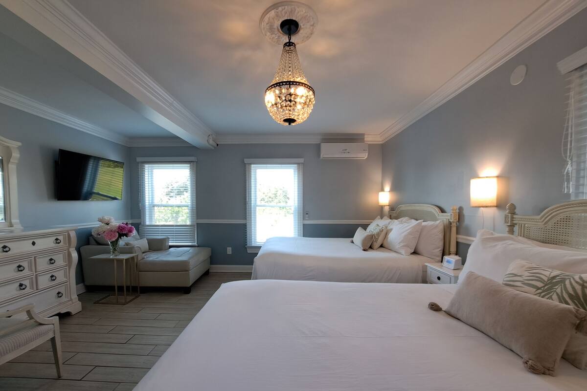 Quarto com duas camas, cômoda, penteadeira e lustre.