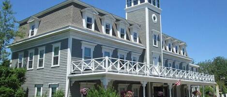 A large, two-story building with a prominent tower and a covered porch.
