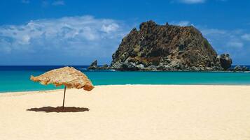 Na praia, guarda-sóis, toalhas de praia