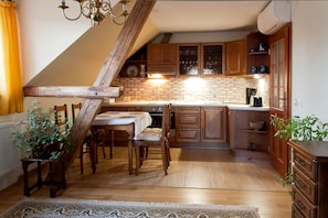 A kitchen with wooden cabinets, a dining table with chairs, and a staircase. - U Prejzků (Lhotka)