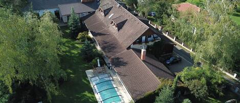 An aerial view of a residential property with a swimming pool, a covered patio, and a fenced yard.