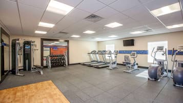 Un gimnasio con cintas de correr, elípticas y pesas sueltas.