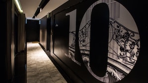 Un pasillo con un gran mural del número 10, piso de mármol y una escalera con ornamentación metálica.