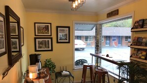 A cozy corner with a coffee station, framed pictures, and a view of the street. - Lava Spa Motel & RV Park (Lava Hot Springs)