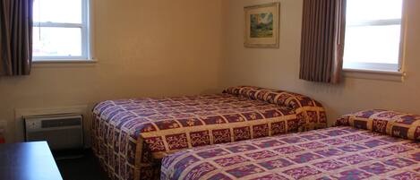 A room with two beds, a desk, and a window with curtains.