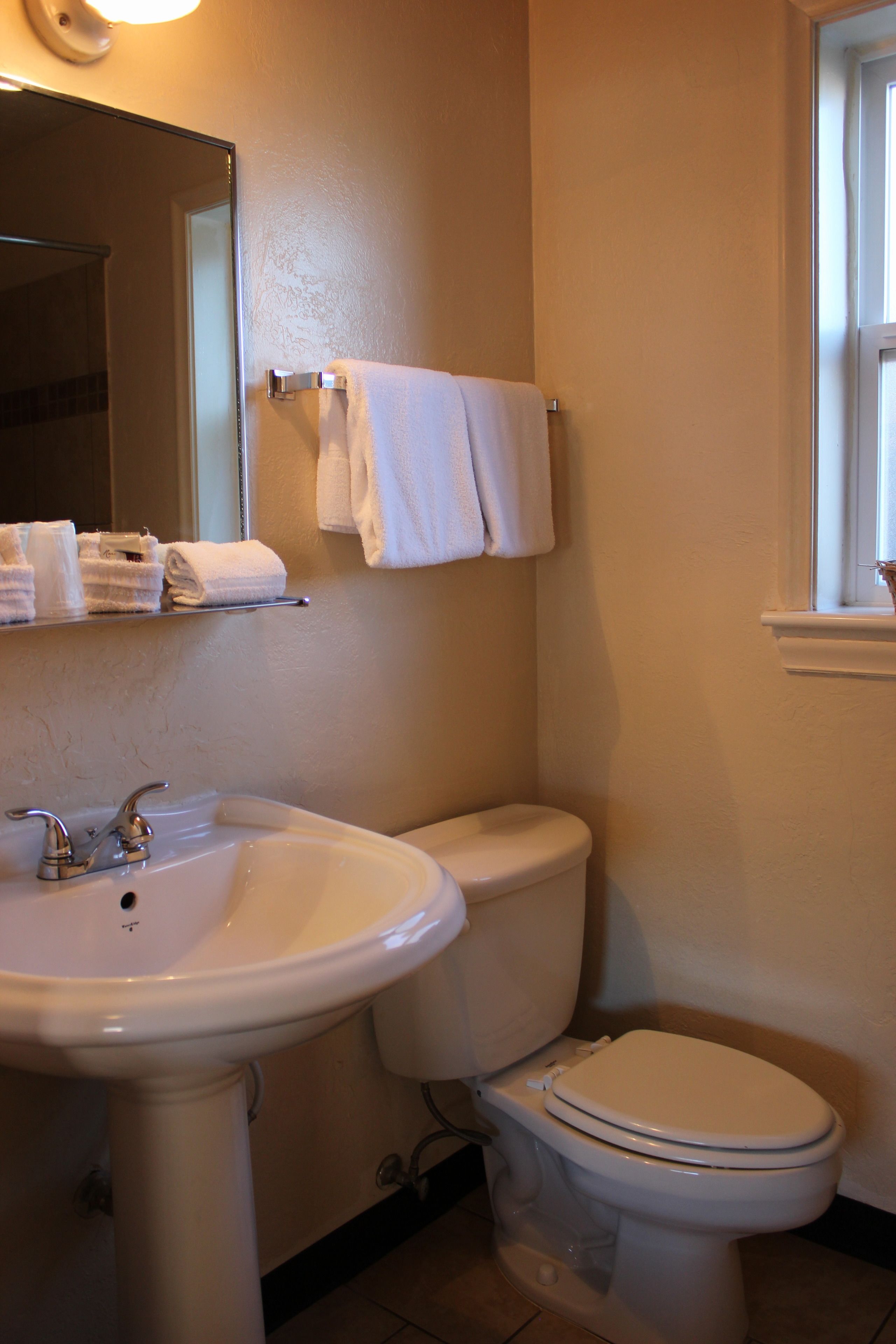 Une salle de bain avec un lavabo, des toilettes et un miroir. Des serviettes sont suspendues sur un porte-serviettes.