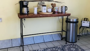 A reception desk with a coffee machine, a trash can, and framed pictures on the wall. - Lava Spa Motel & RV Park (Lava Hot Springs)