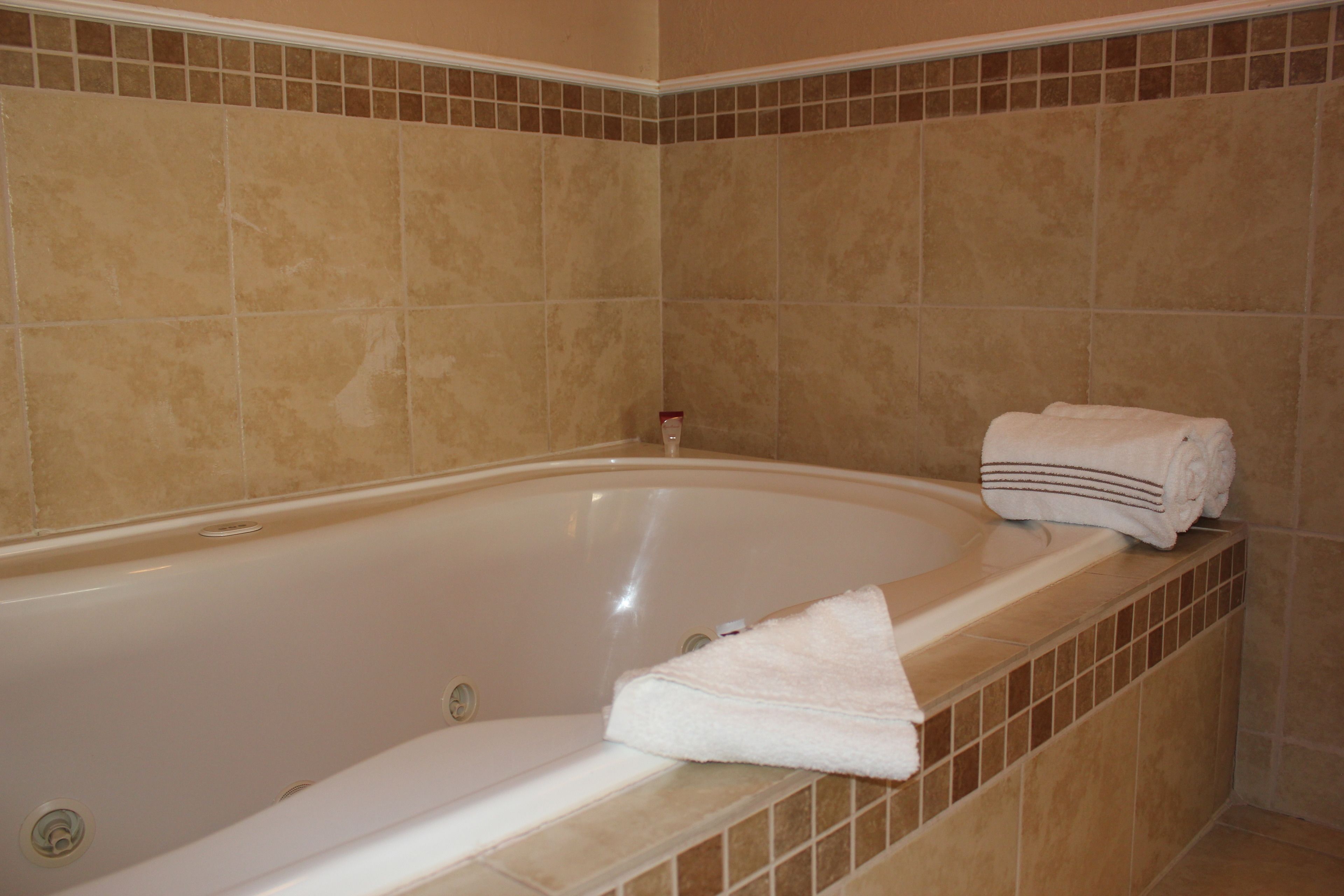 A bathroom with a bathtub, tiled walls, and a towel on the edge.