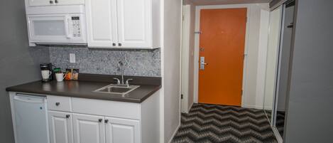 A compact kitchen with white cabinets, a microwave, and a sink.