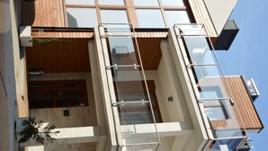 Ein modernes Gebäude mit Glasbalkon, Holzterrasse und blauem Himmel.