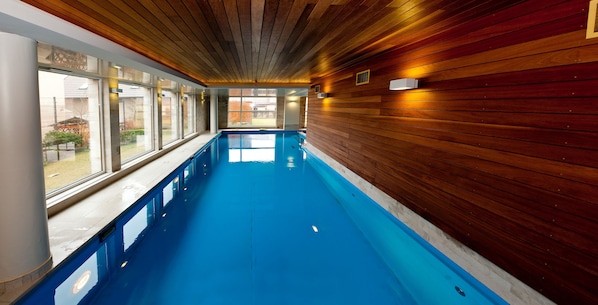 Una piscina interior larga con paredes de madera y ventanas amplias.