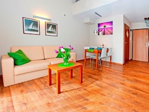 Uma sala de estar com sofá, mesa de centro e área de jantar com mesa e cadeiras.