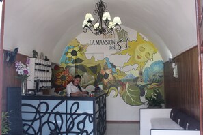 A hotel reception area with a mural, a receptionist, and a reception desk. - La Mansión del Sol (Arequipa)