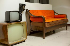 A vintage wooden sofa with orange cushions and a television set on a wooden table. - La Mansión del Sol (Arequipa)