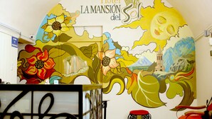 A mural with the text "Hotel La Mansión del Sol" and a sun with a face.