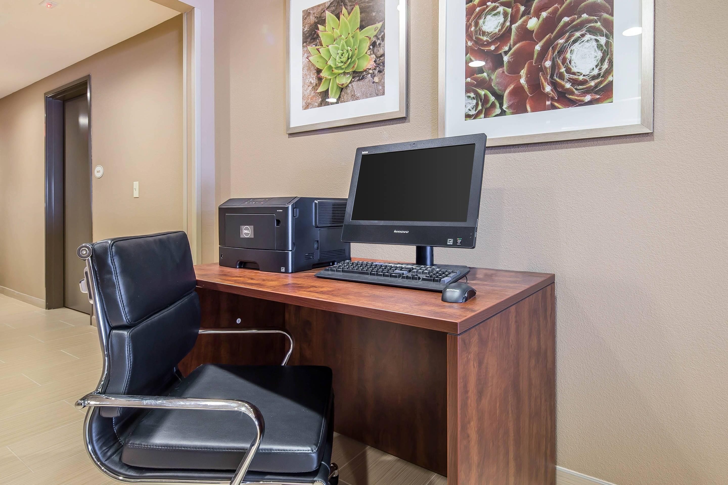 A hotel office with a desk, computer, and chair.
