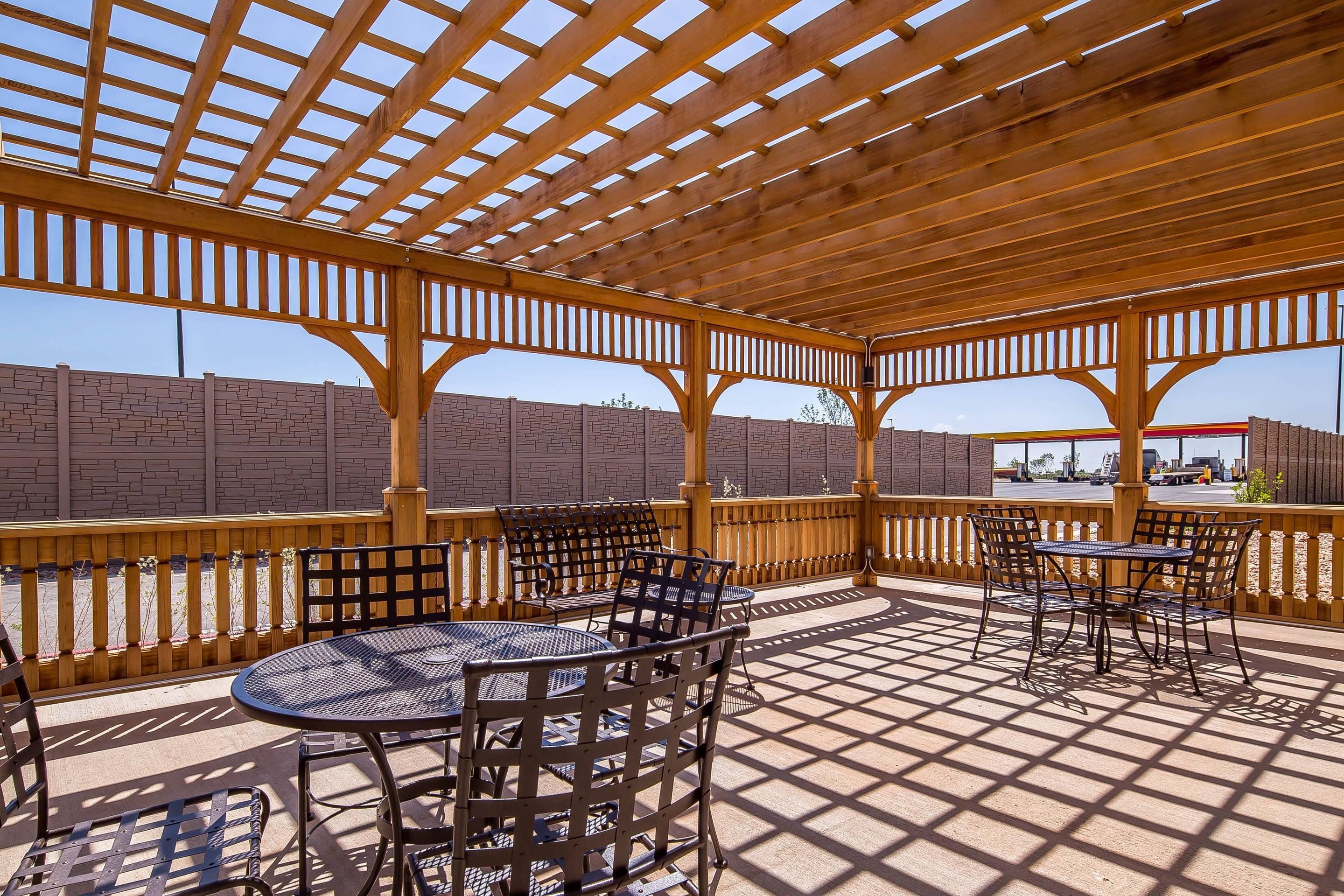 An outdoor patio with wooden pergola, tables, and chairs.