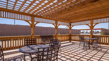 An outdoor patio with wooden pergola, tables, and chairs.