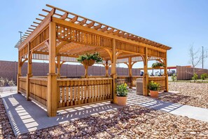 A wooden gazebo with a bench and potted plants. - Suburban Studios Midland I-20 (Midland)