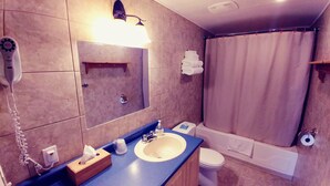 Un baño con lavamanos, espejo, toallero, inodoro y bañera.