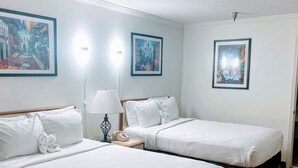 Habitación de hotel con dos camas individuales, una mesita de noche con lámpara y teléfono.